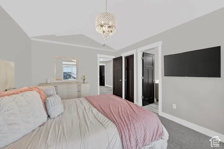 Bedroom featuring light carpet, suspended lighting, and ensuite bath