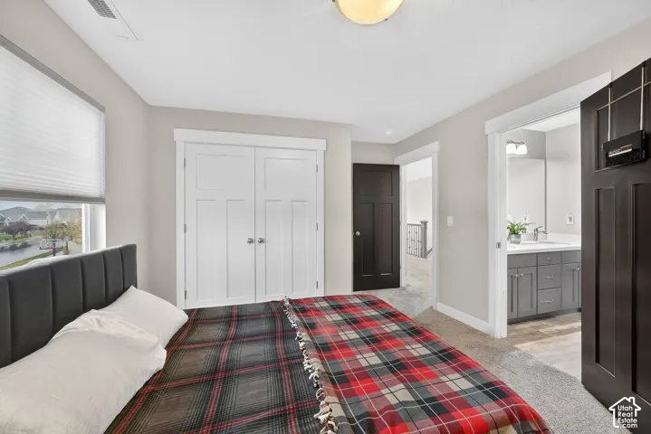 Bedroom with light carpet, a closet, and ensuite bath