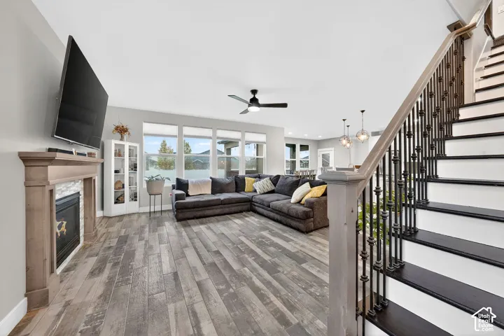 Living room with light wood-style floors, a glass covered fireplace, and a ceiling fan