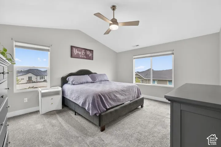 Bedroom with light carpet, vaulted ceiling, and ceiling fan