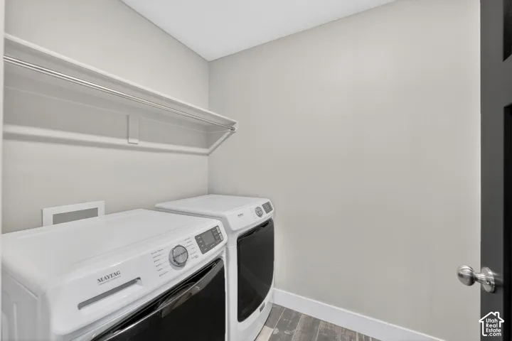 Laundry area with dark wood finished floors and independent washer and dryer