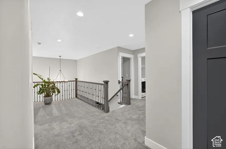 Corridor featuring an upstairs landing, carpet floors, and a chandelier