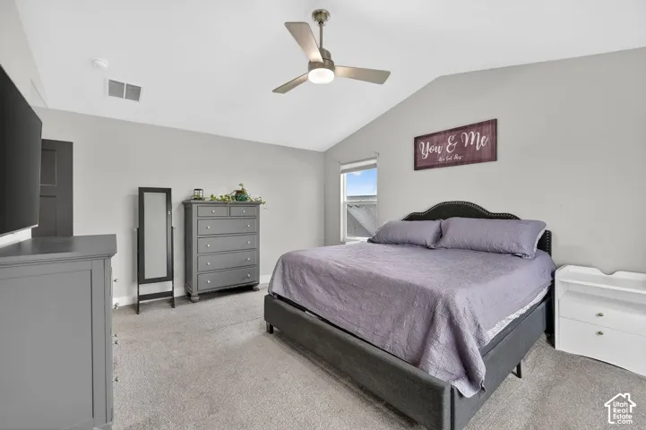 Bedroom featuring vaulted ceiling, light carpet, and ceiling fan