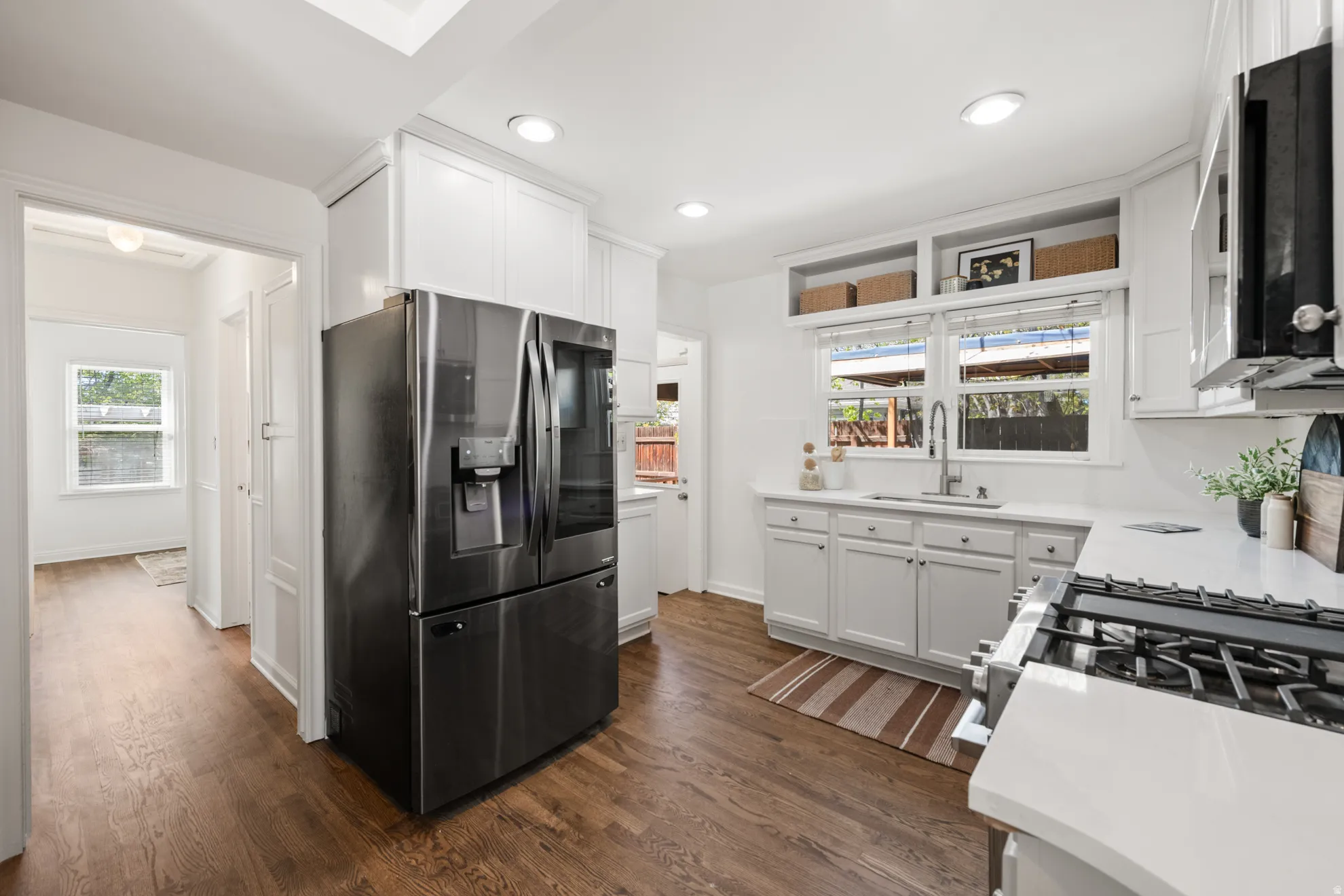 Kitchen with stainless steel appliances, white cabinetry, dark wood finished floors, light stone countertops, and recessed lighting
