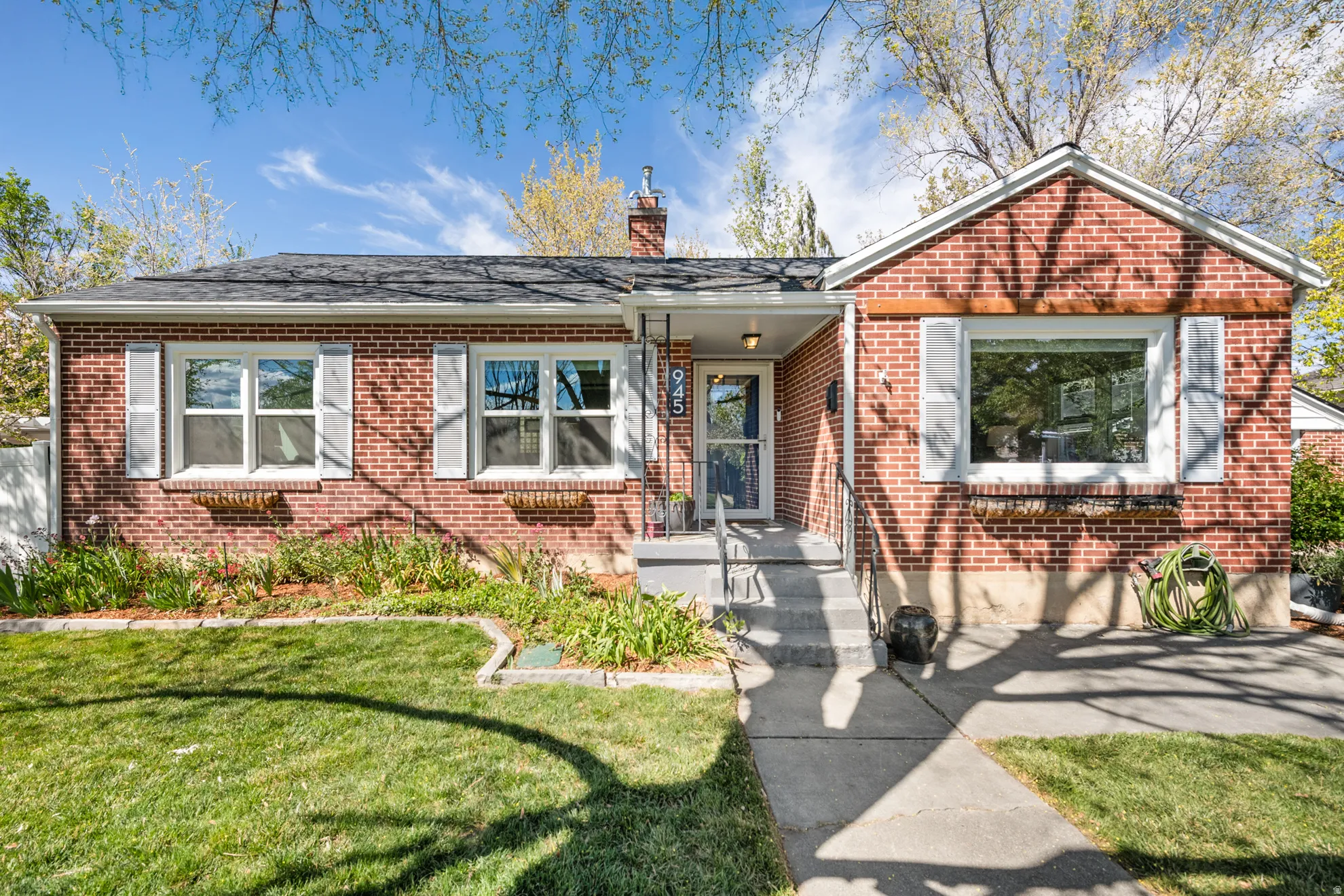 Bungalow-style house featuring a front lawn, brick siding, and a chimney