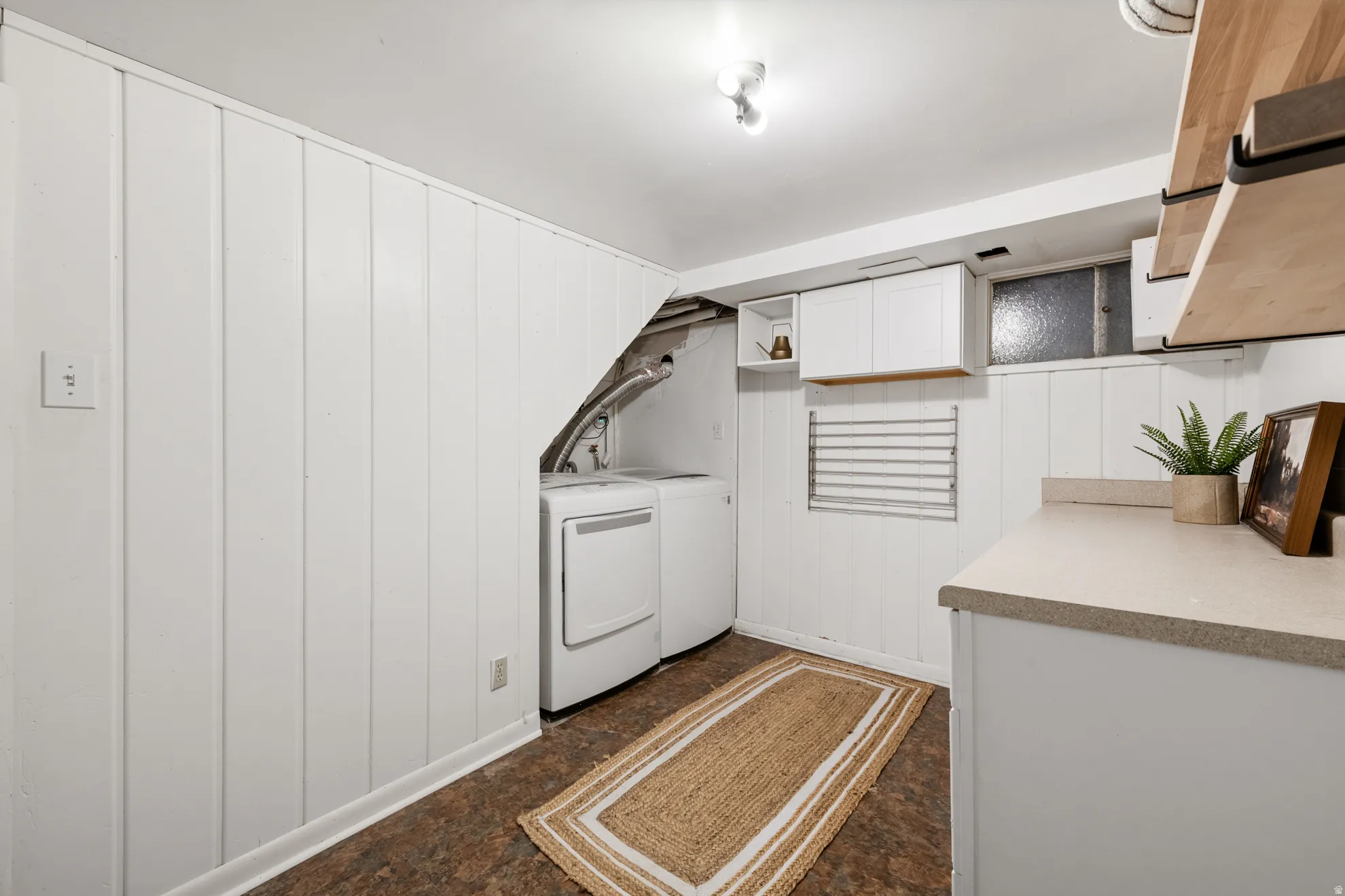 Laundry area with washing machine and dryer, wooden walls, and cabinet space