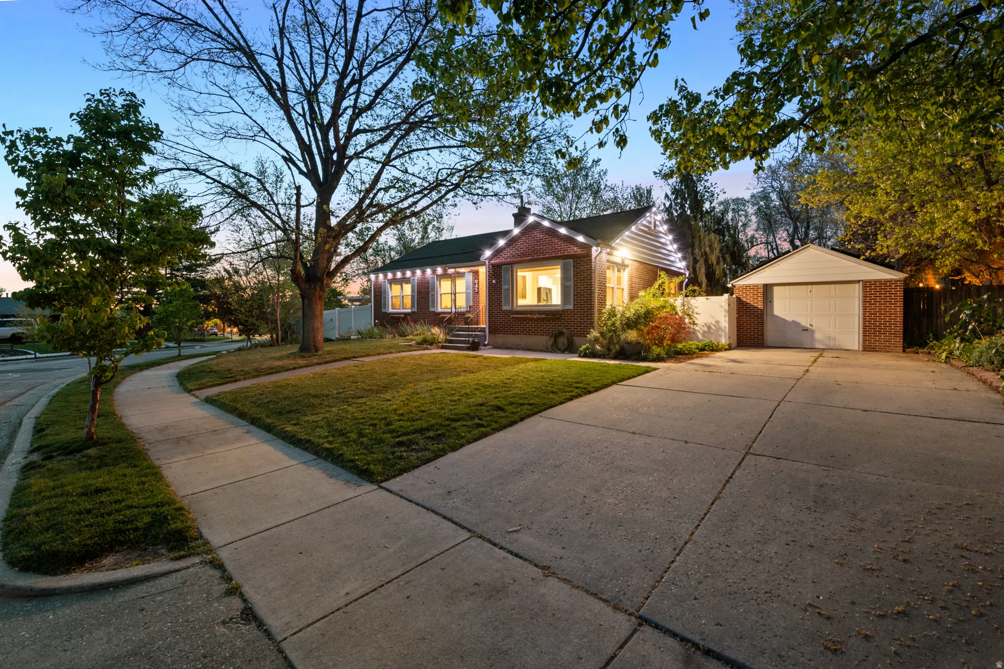 View of front of house with an outbuilding, brick siding, driveway, and a garage