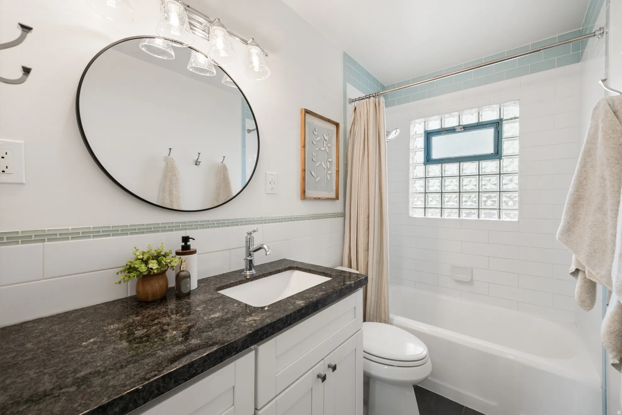 Full bathroom featuring shower / bathtub combination with curtain, tile walls, vanity, and wainscoting