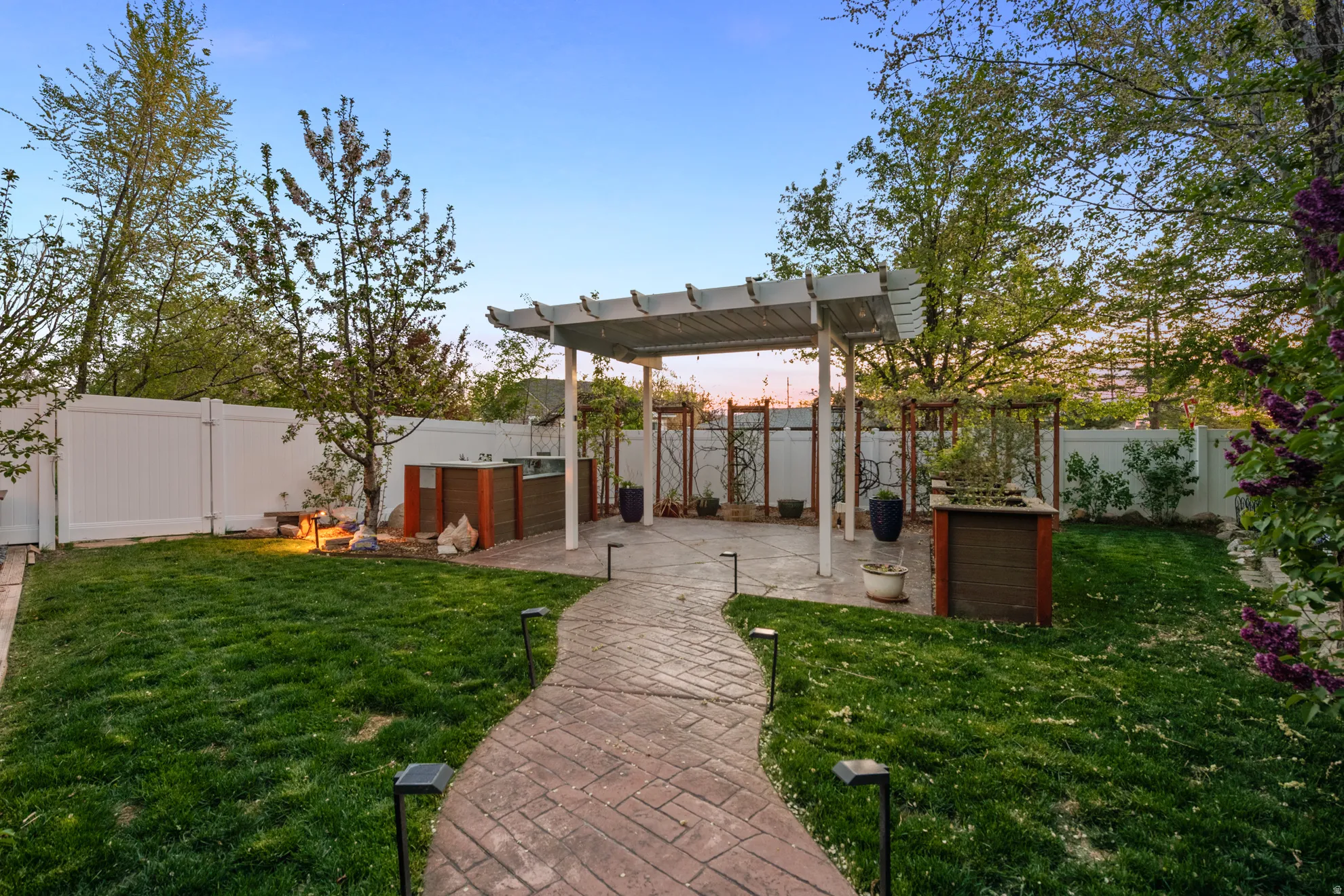 Yard at dusk with a patio, a fenced backyard, and a pergola