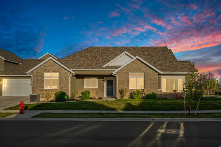 View of front facade with a lawn, covered porch, an attached garage,