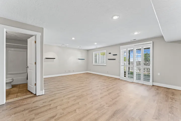 Basement with a textured ceiling, light wood-style flooring, and recessed lighting