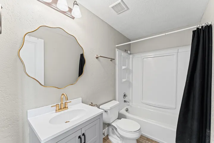 Bathroom with vanity, a textured ceiling, shower / tub combo with curtain, and a textured wall