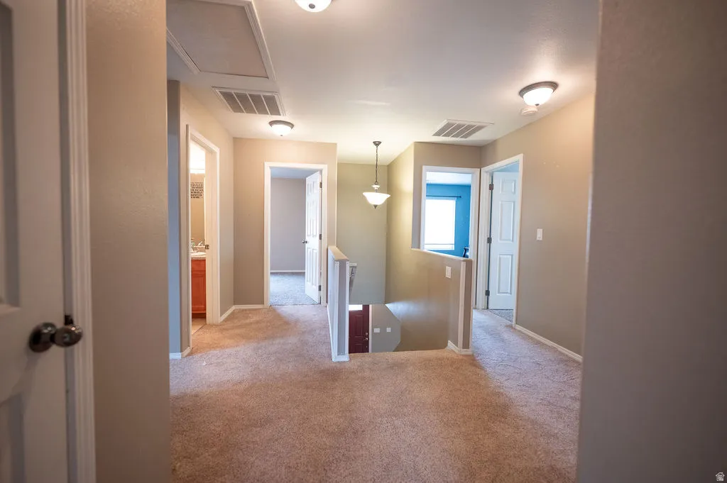Hallway with an upstairs landing and light carpet