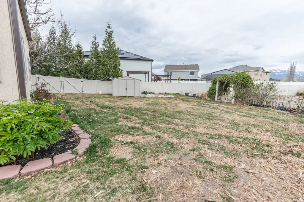 Fenced backyard featuring a storage shed and a gate