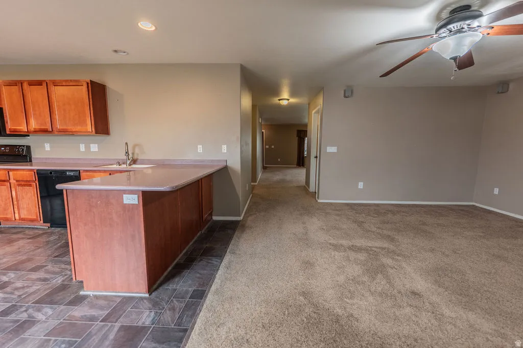 Kitchen featuring wood finish cabinets, light countertops, a peninsula, ceiling fan, and black appliances