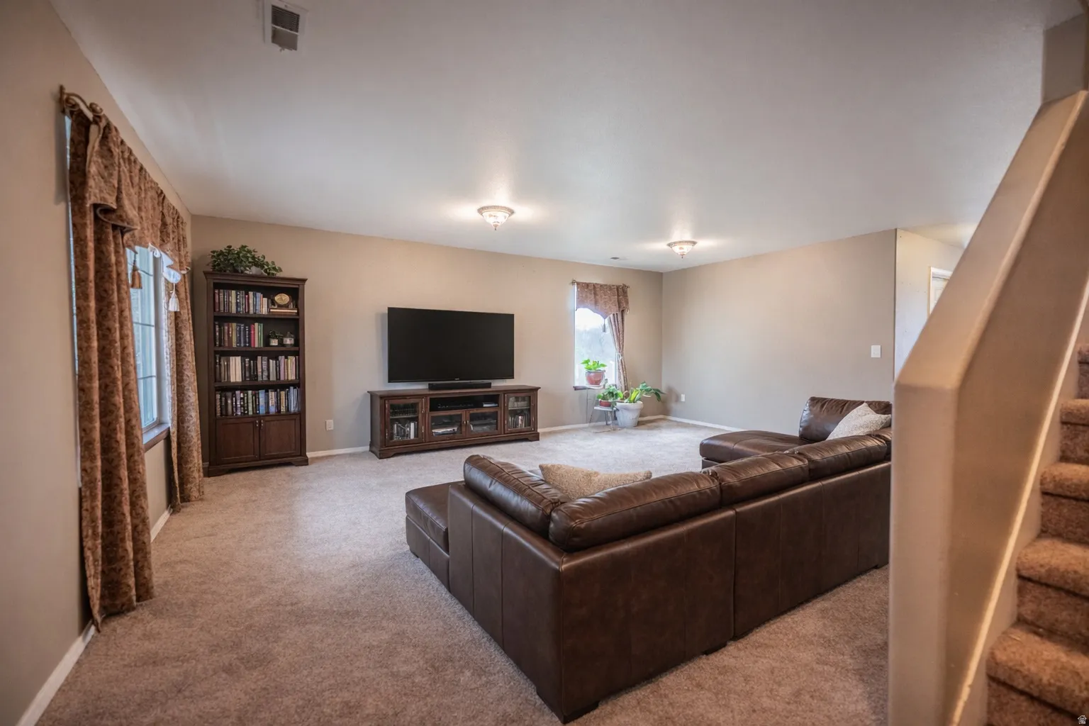 Carpeted living room with stairway and baseboards