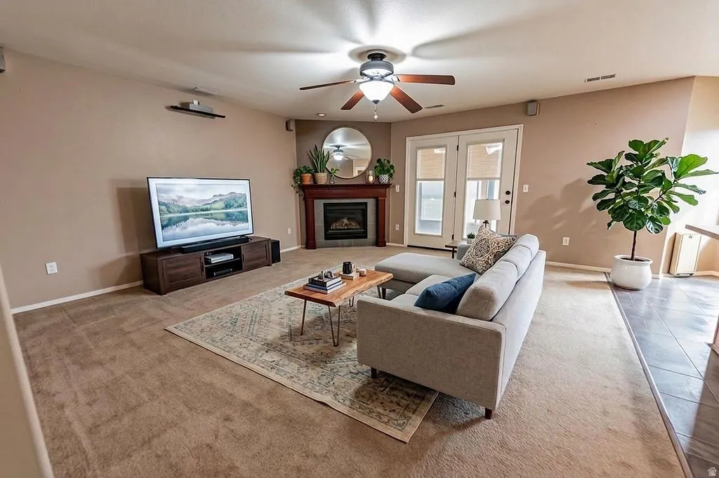 Living room featuring a fireplace, ceiling fan, and light colored carpet