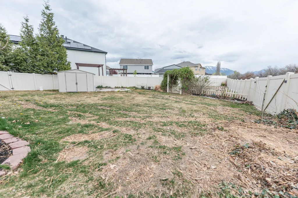 Fenced backyard featuring a shed and a gate