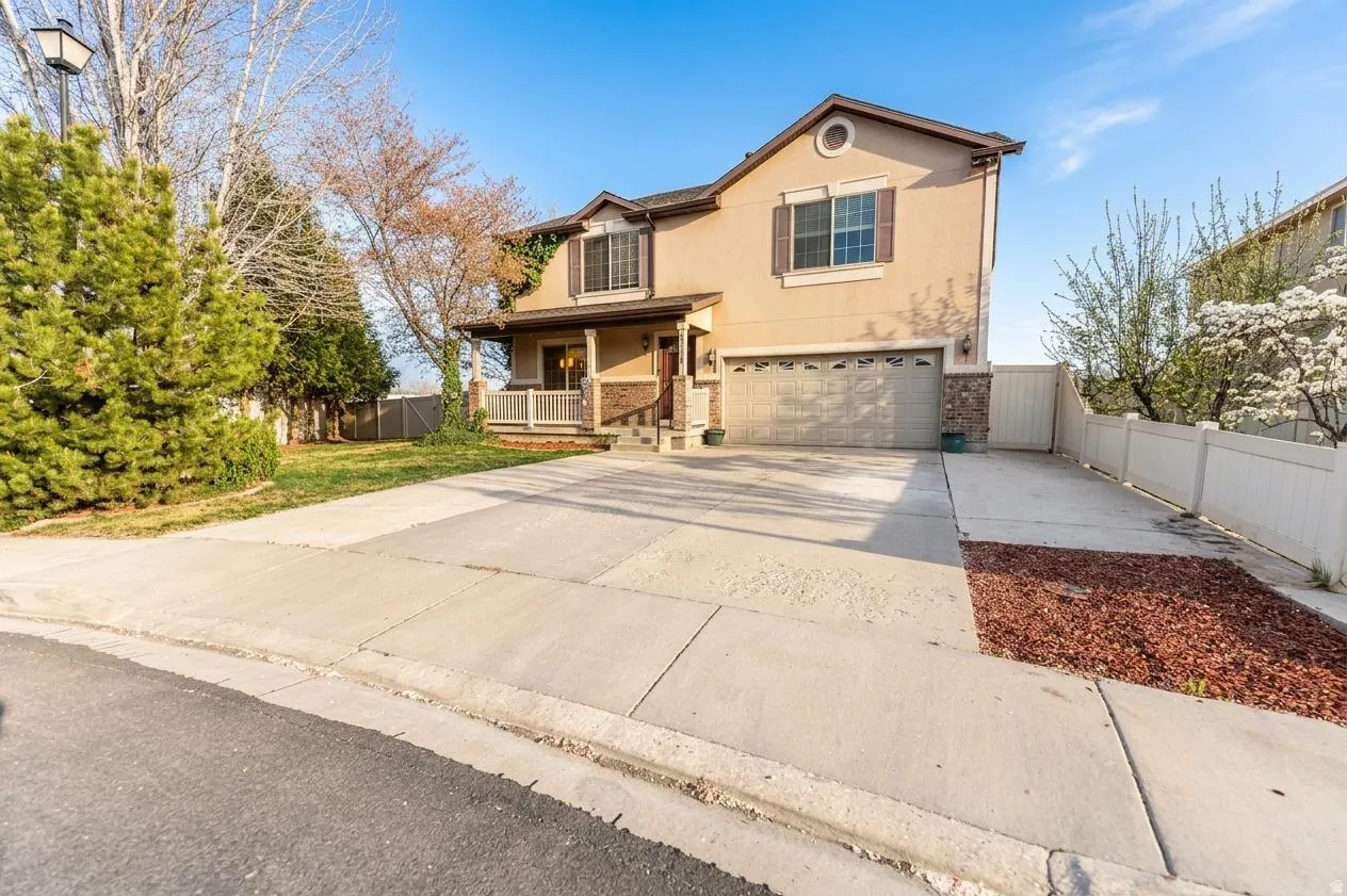 Traditional home with a porch, a garage, stucco siding, concrete driveway, and a gate