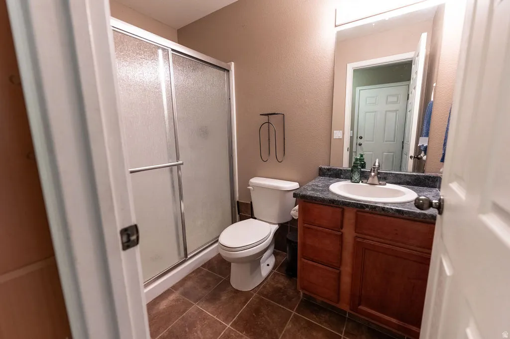Bathroom featuring vanity, a shower stall, dark tile patterned floors, and a textured wall