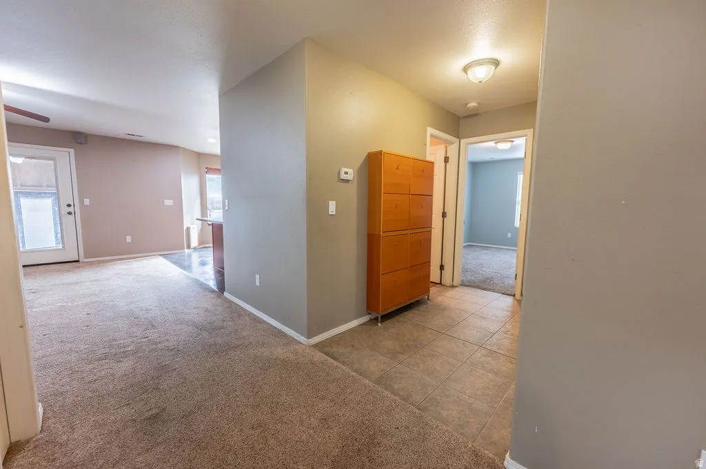 Corridor featuring light colored carpet and baseboards