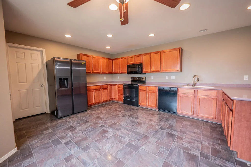 Kitchen featuring black appliances, light countertops, ceiling fan, recessed lighting, and stone finish floors