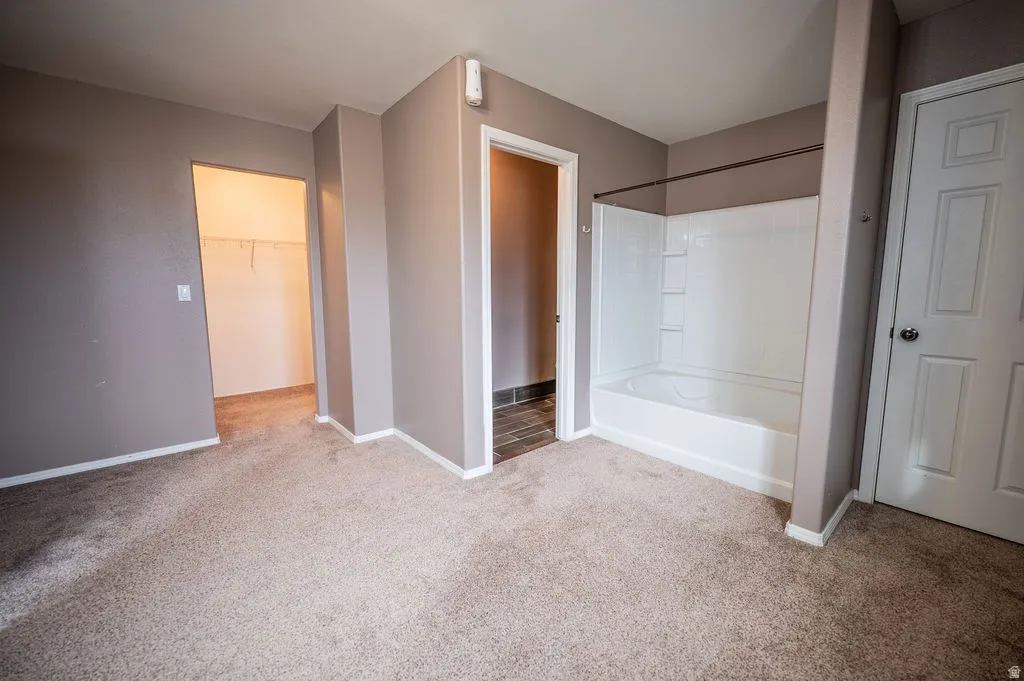 Full bathroom with light carpet, a walk in closet, and bathing tub / shower combination