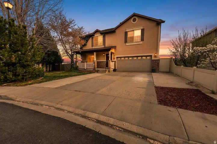 Traditional-style home with covered porch, a garage, stucco siding, and concrete driveway