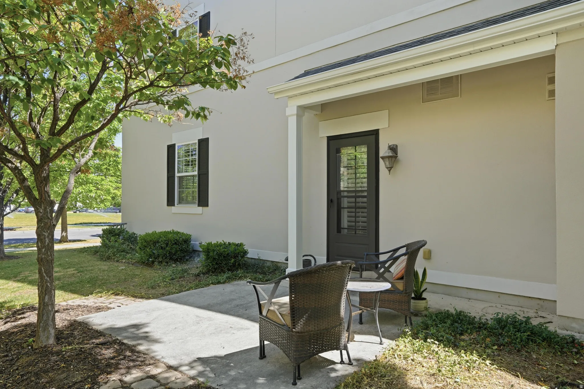 Covered patio with a black screen door and exterior wall lantern
