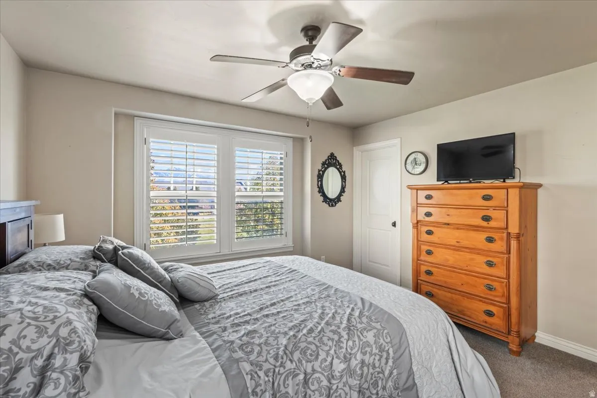 Bedroom with dark carpet and ceiling fan