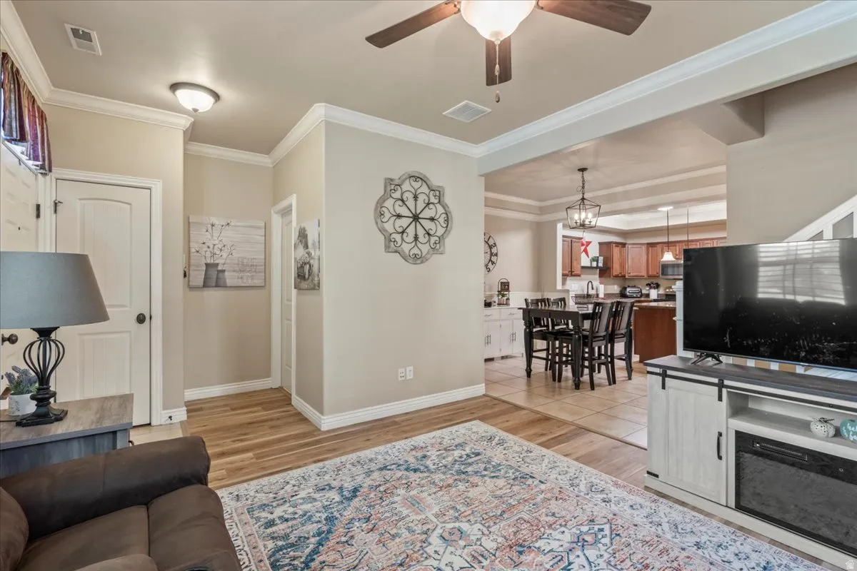 Living room featuring ornamental molding, light wood-style flooring, and a ceiling fan