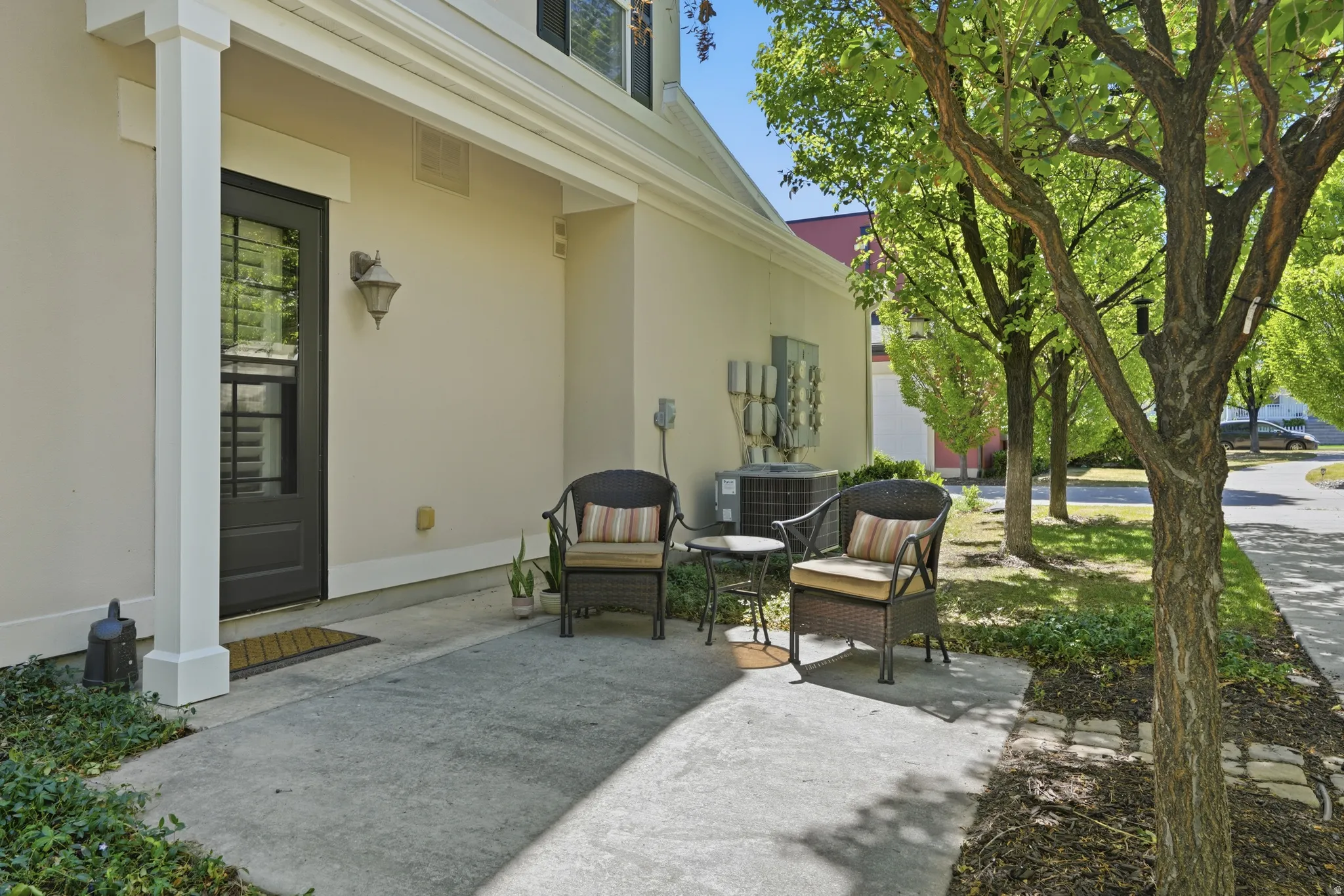 Inviting front entry patio with a black paneled door, decorative wall sconce, and white column detail