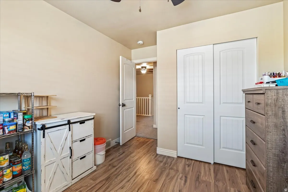 Bedroom featuring dark wood-style flooring, a closet, and ceiling fan
