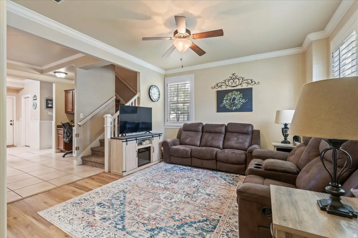 Living area featuring light wood finished floors, ornamental molding, and ceiling fan