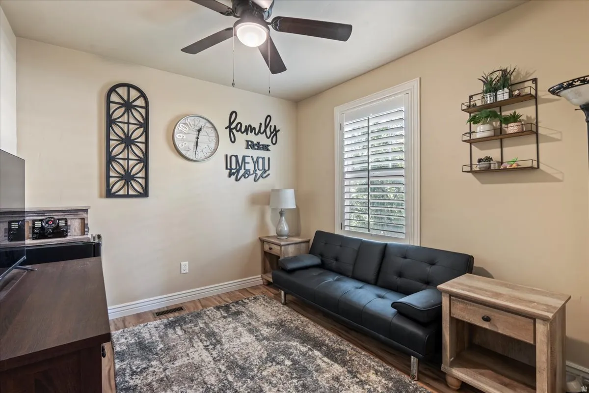 Living room with dark wood-style flooring and a ceiling fan