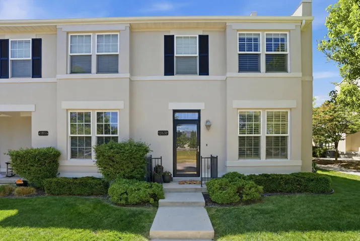 Stucco exterior featuring multiple windows with shutters, a dark-framed glass paneled entry door, and a concrete walkway