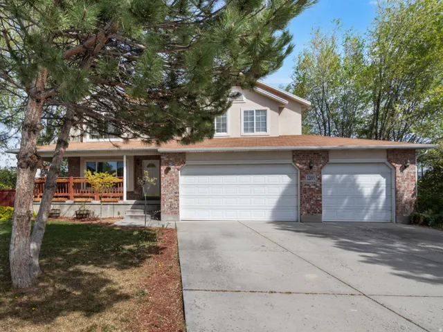 Two-story residence featuring a two-car garage with individual doors, a brick facade accent, and a front deck
