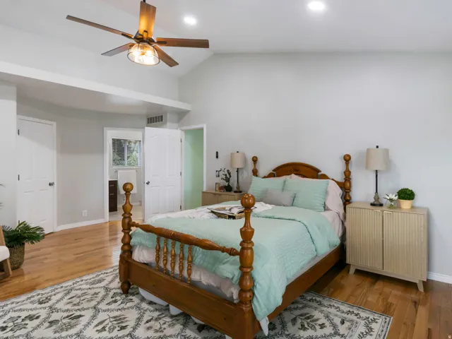 Spacious primary bedroom featuring wood-finish flooring, vaulted ceilings, and recessed lighting