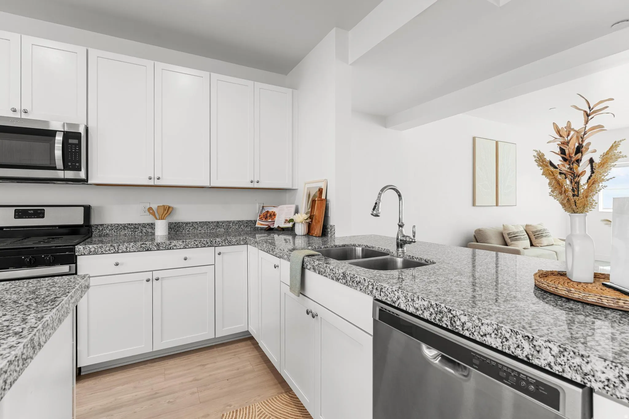 Kitchen with stainless steel appliances, white cabinets, light wood-style floors, and open floor plan