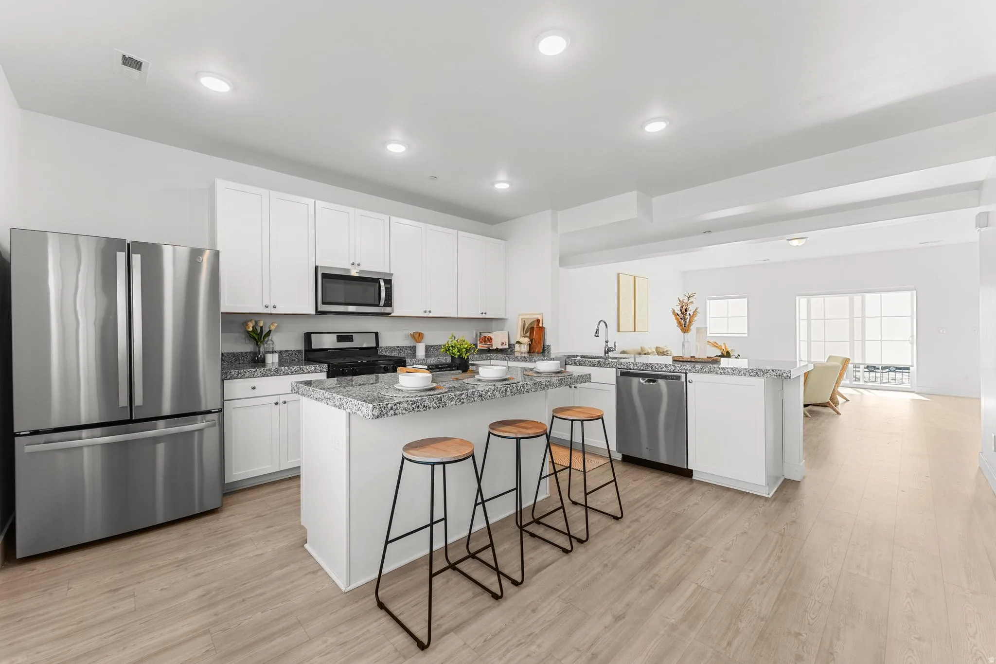 Kitchen featuring stainless steel appliances, white cabinetry, a center island, a kitchen breakfast bar, and light wood-style flooring