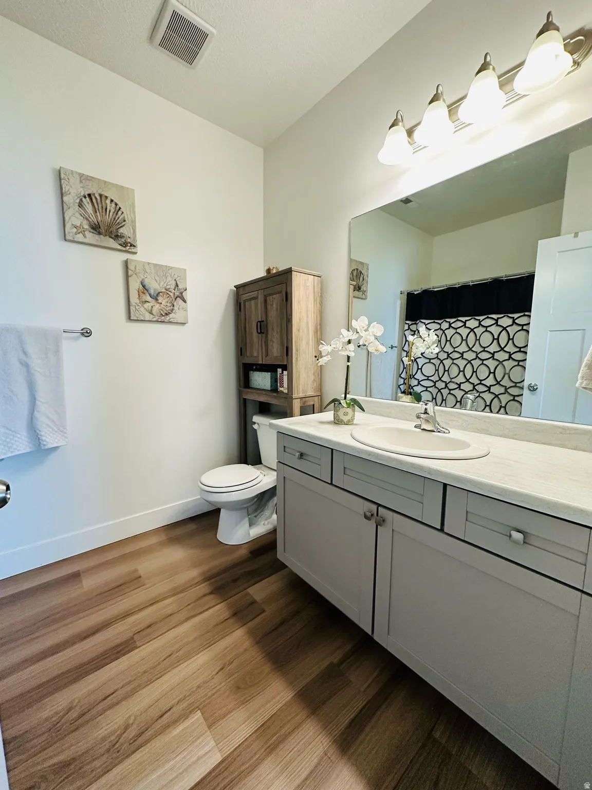 Full bath with a shower with curtain, vanity, and dark wood-style flooring