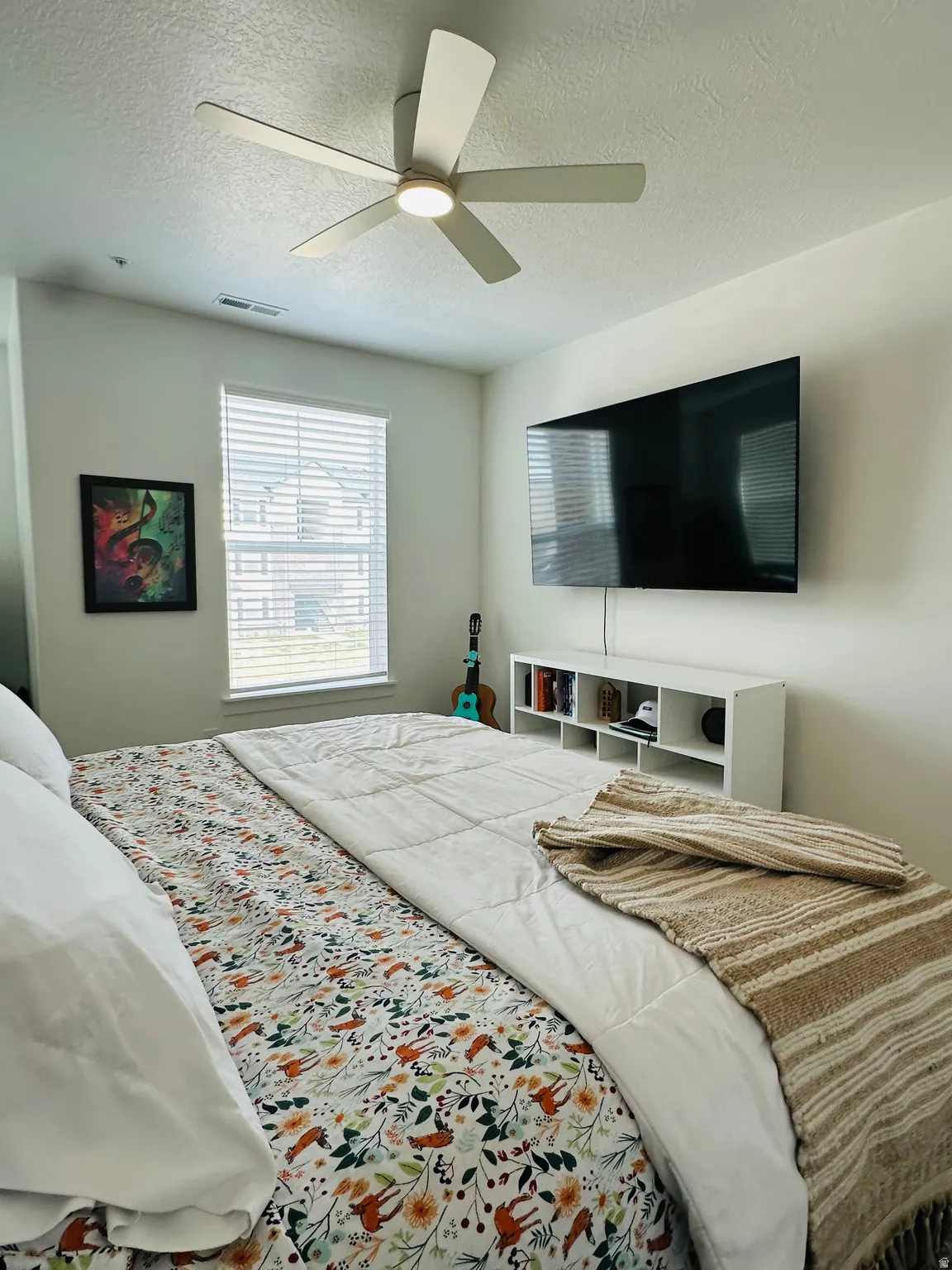 Bedroom with a ceiling fan and a textured ceiling