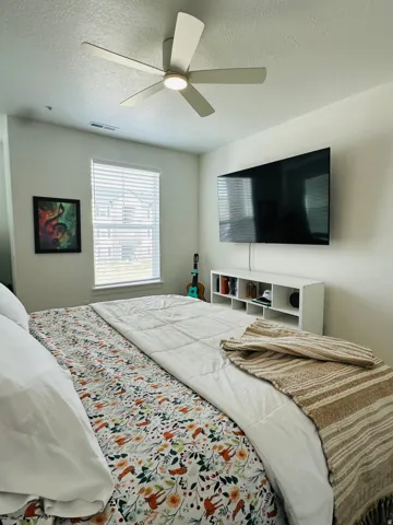 Bedroom with a ceiling fan and a textured ceiling