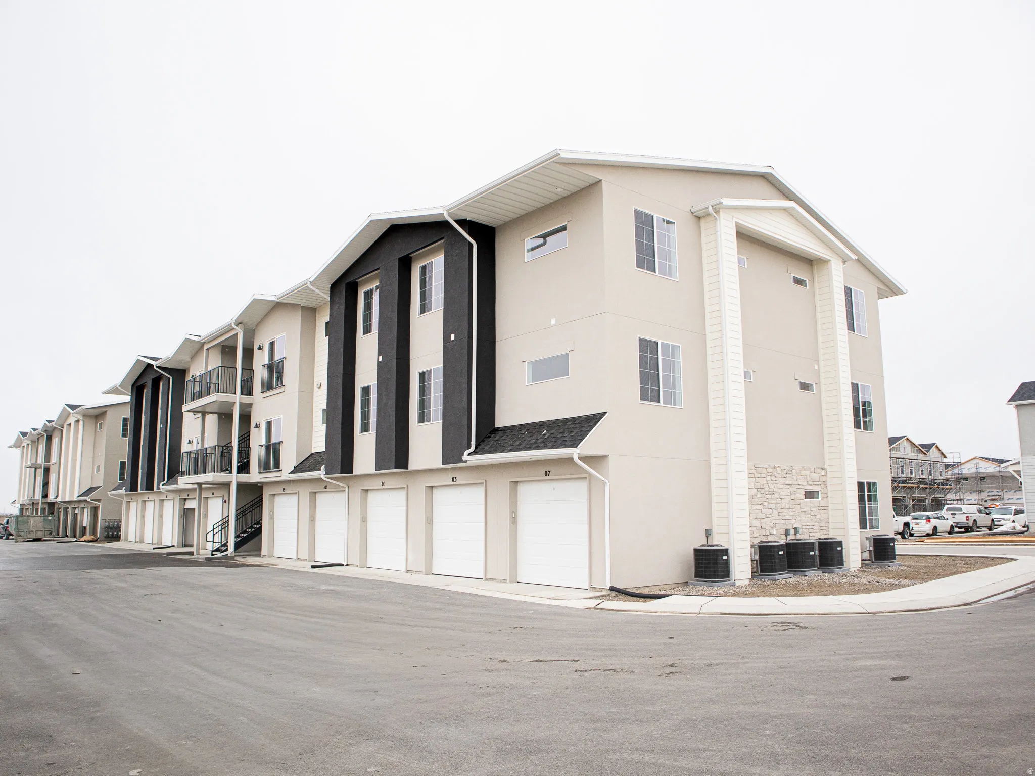 Rear view of building with one car garage and additional parking space.