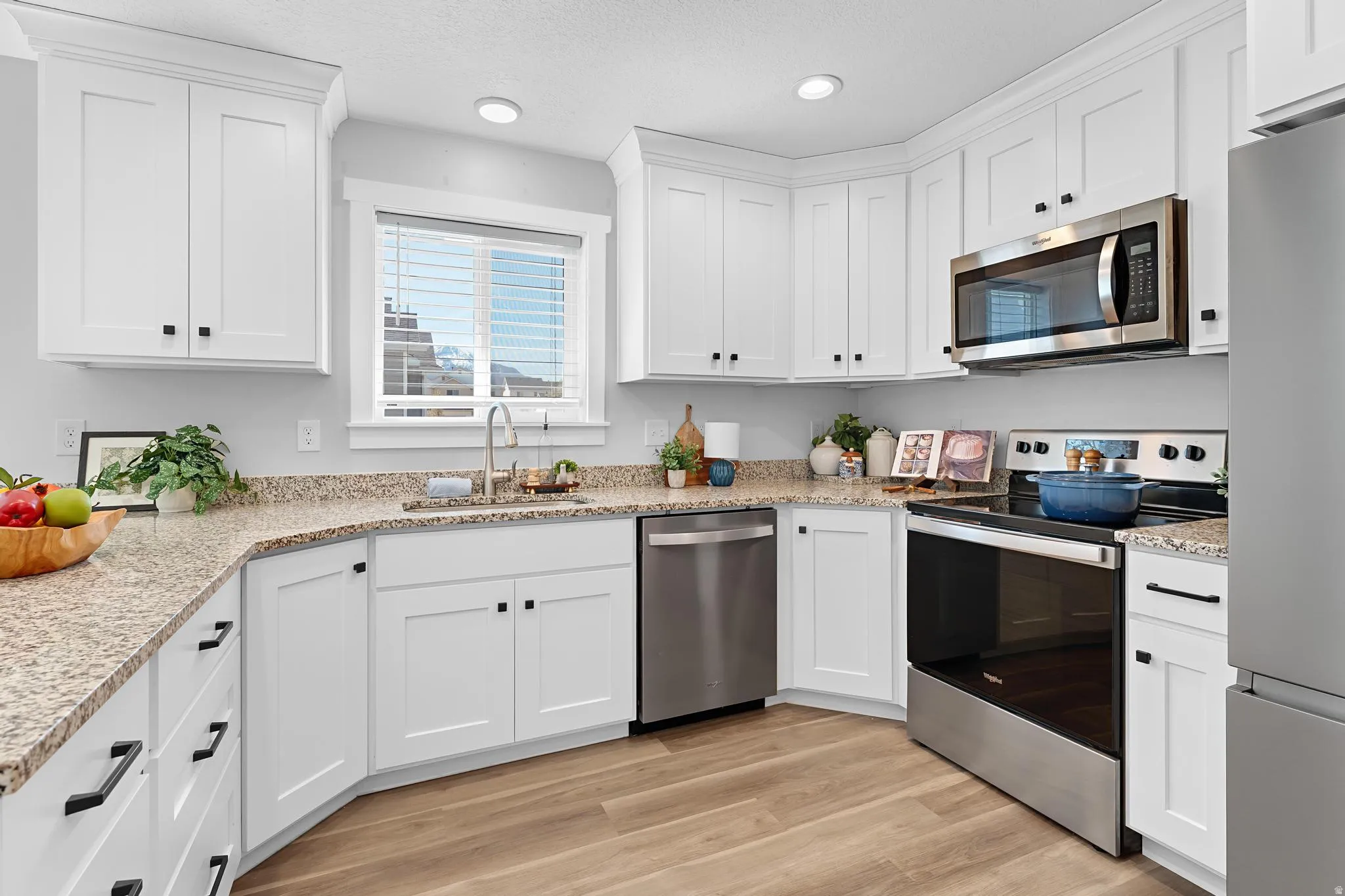 Kitchen featuring stainless steel appliances, light stone countertops, white cabinets, a textured ceiling, and recessed lighting