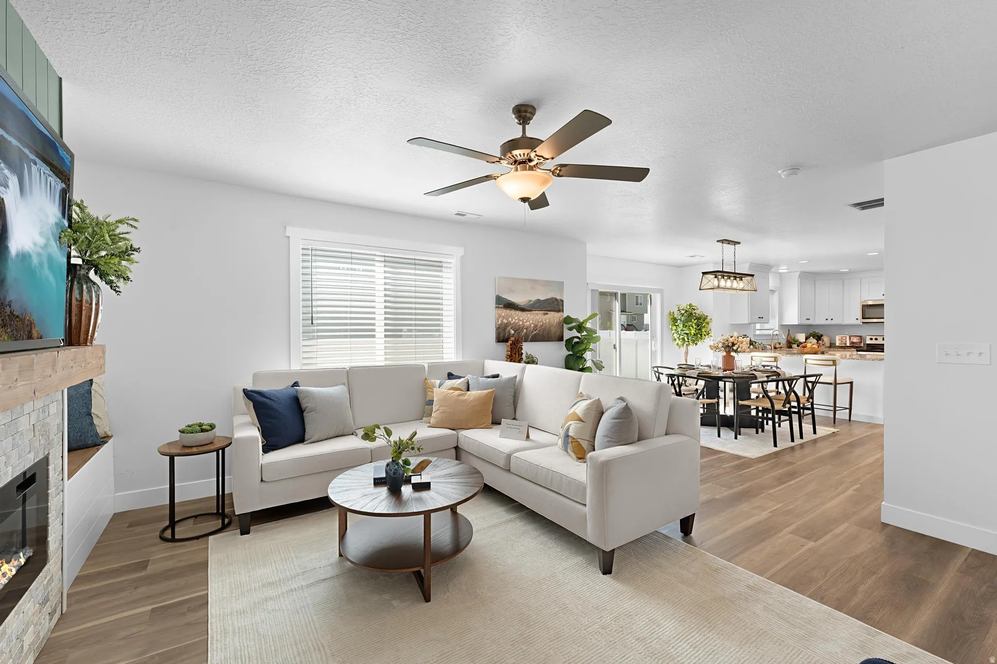 Living room with light wood-style floors, a glass covered fireplace, plenty of natural light, and a textured ceiling