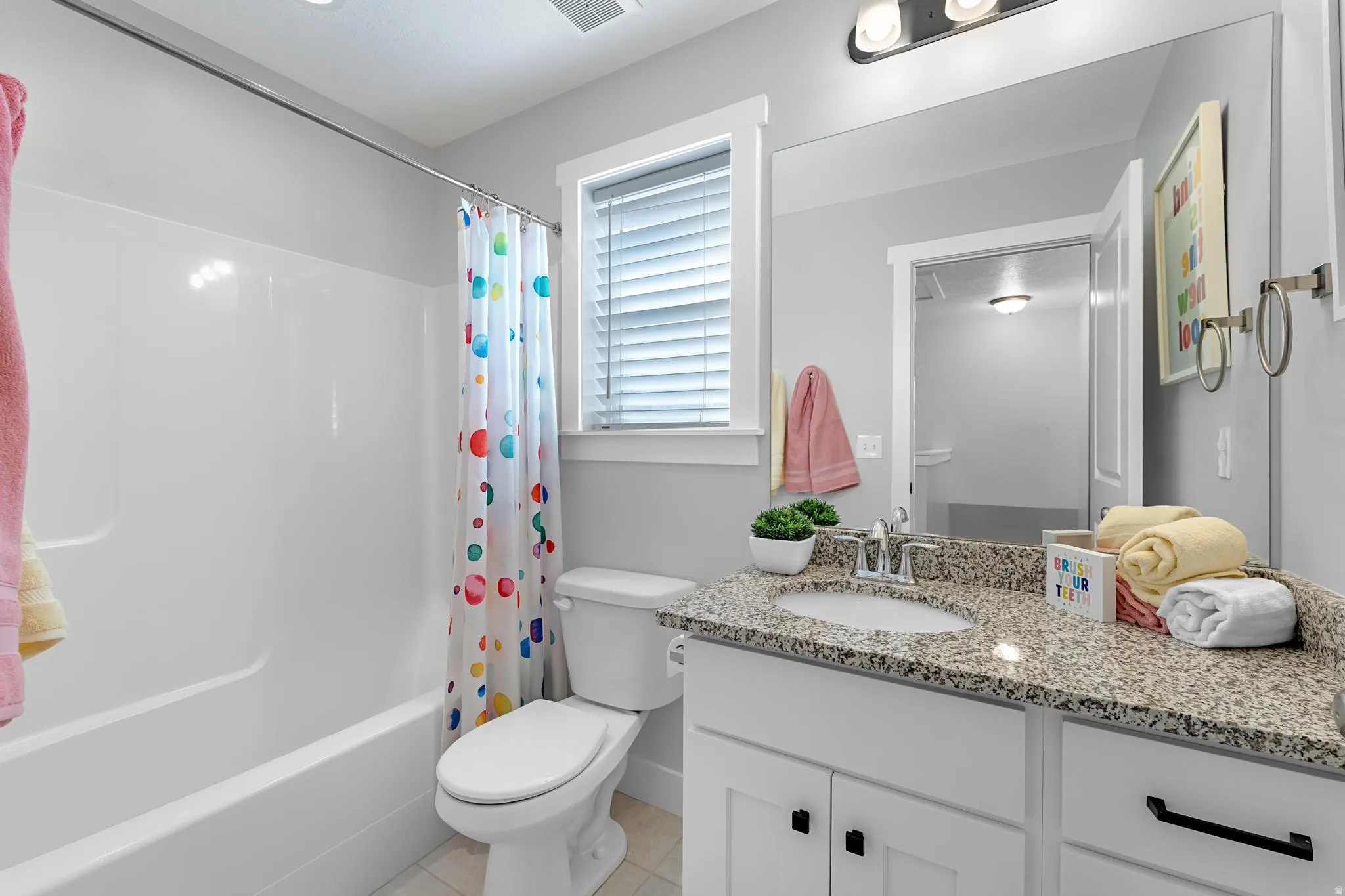 Full bath featuring vanity, shower / bath combo with shower curtain, and light tile patterned flooring