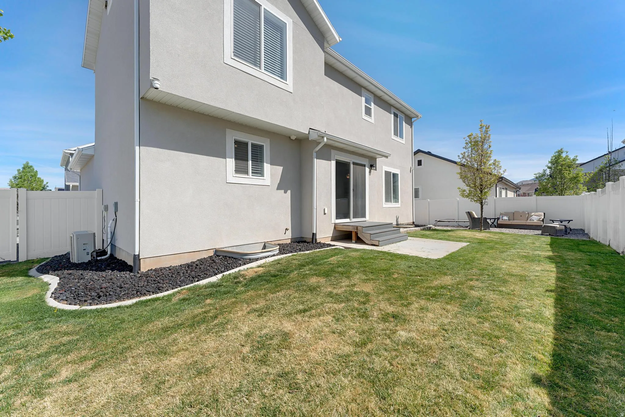 Rear view of house with a fenced backyard, stucco siding, a patio, and an outdoor living space