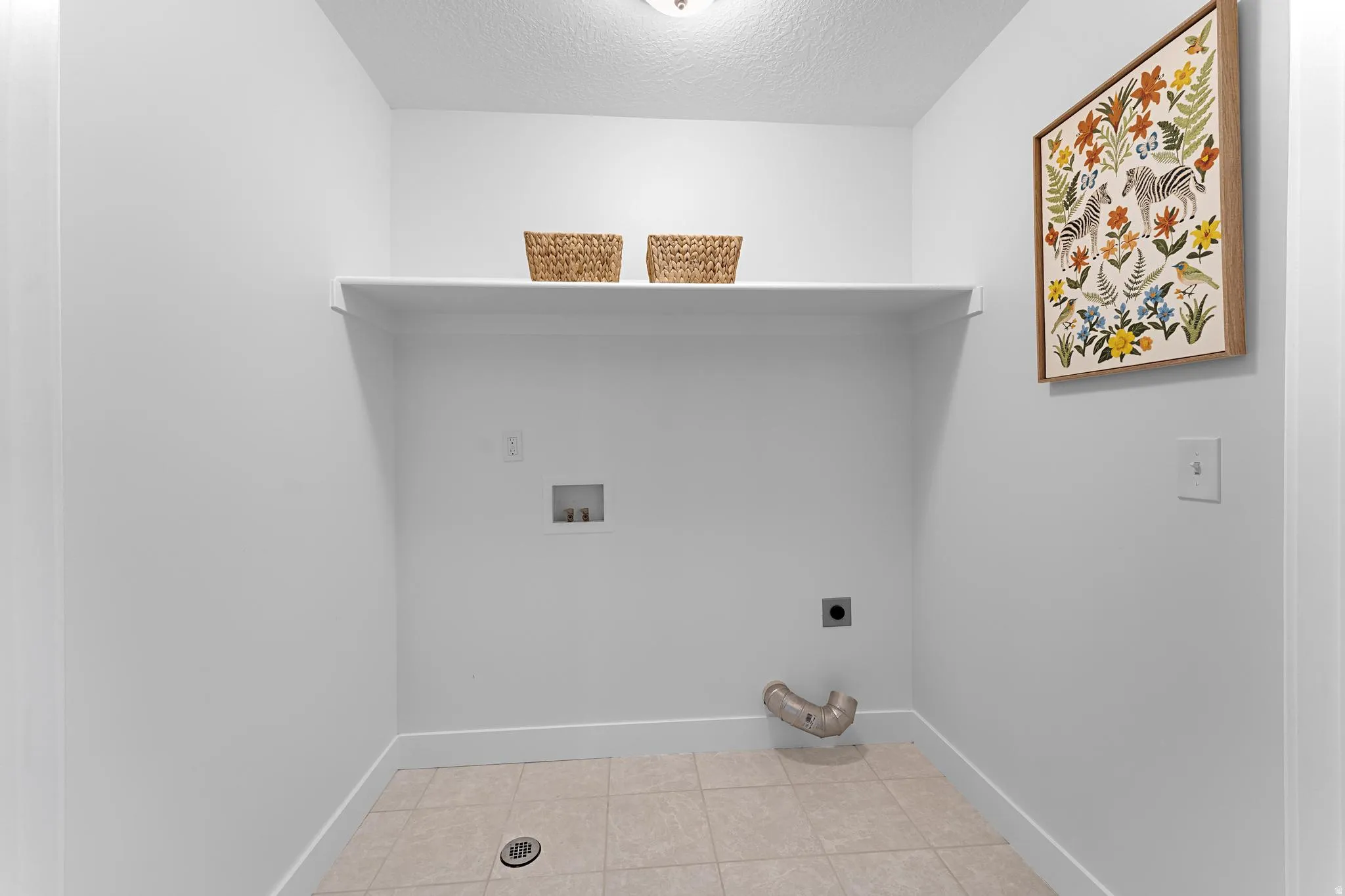 Laundry room featuring a textured ceiling, electric dryer hookup, washer hookup, and light tile patterned flooring