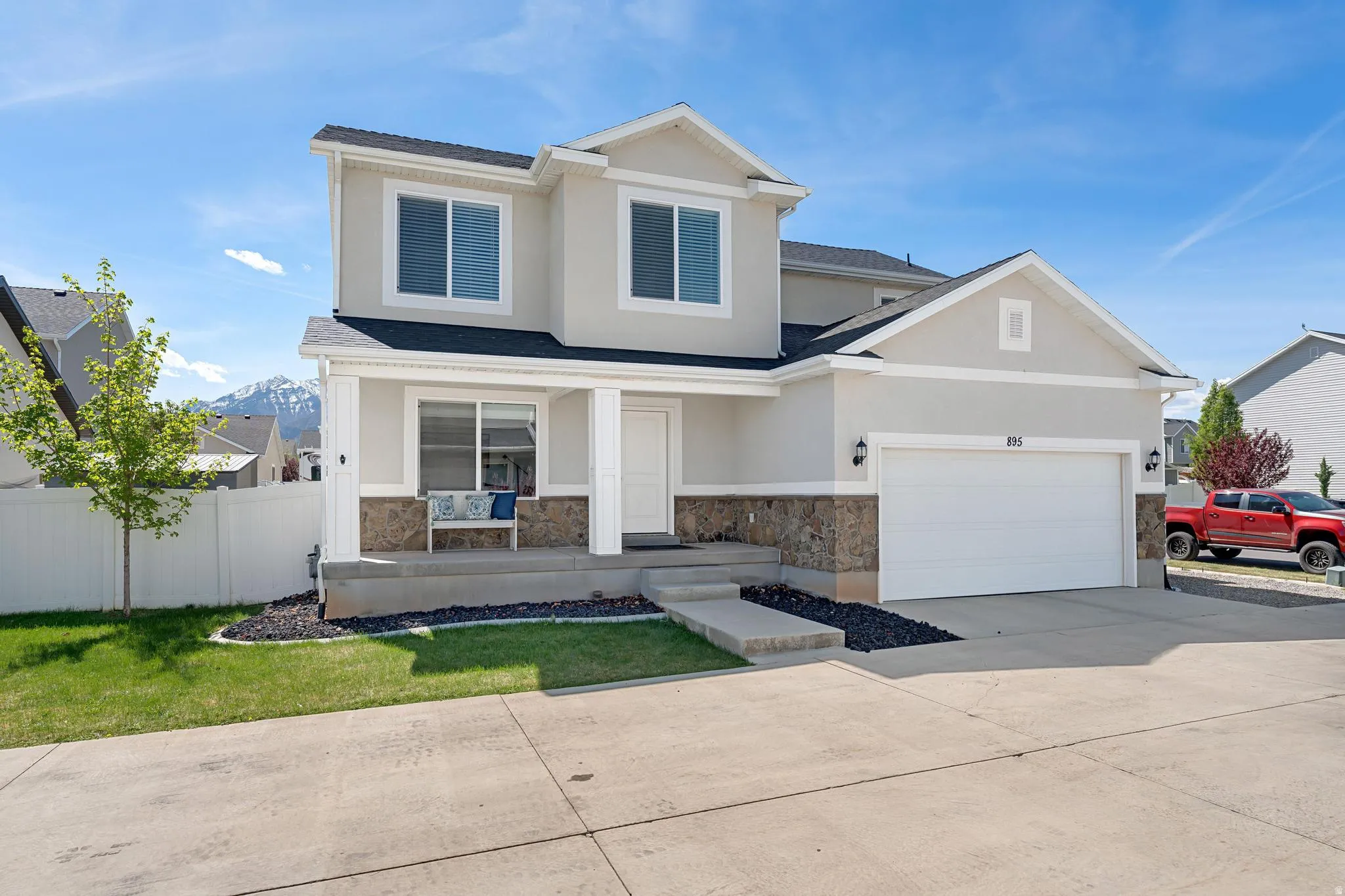 View of front of house featuring a porch, stucco siding, driveway, a garage, and stone siding